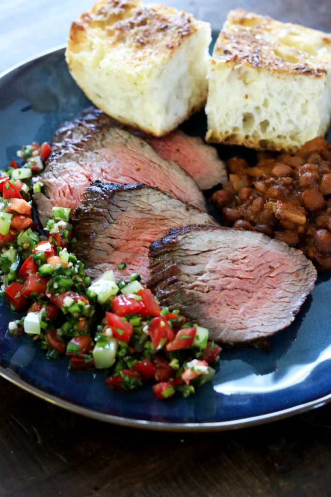 A plate of Santa Maria style barbecue, with tri-tip, beans, salsa, and garlic bread